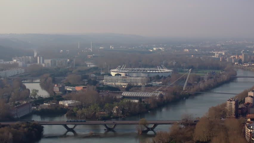 Aerial view showing Stadium Municipal beside Garonne river, highlighting Toulouse cityscape and architectural elements