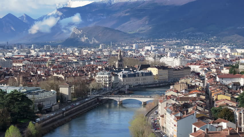 Panoramic view of Grenoble, France, showcasing the Isere river, urban landscape, Saint Andre church tower and the French Alps