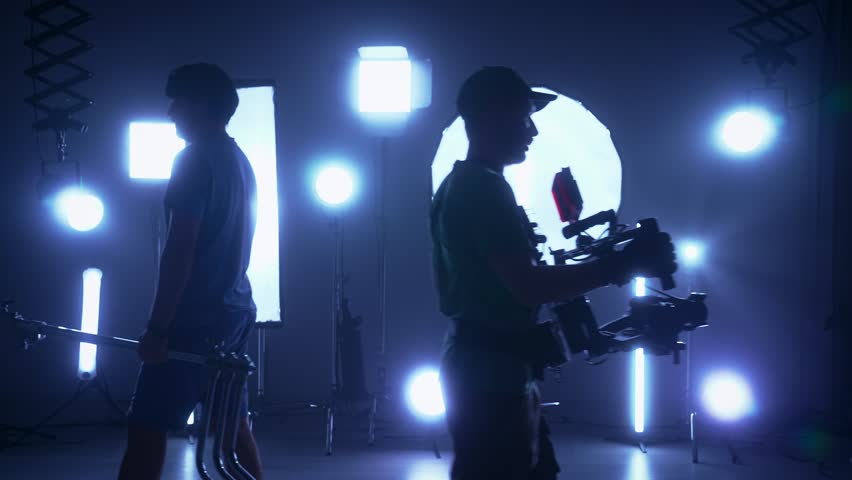 Professional shooting pavilion with lighting equipment. The process of preparing for the shooting of a music video. Cameraman and crew in Backstage. Slow motion
