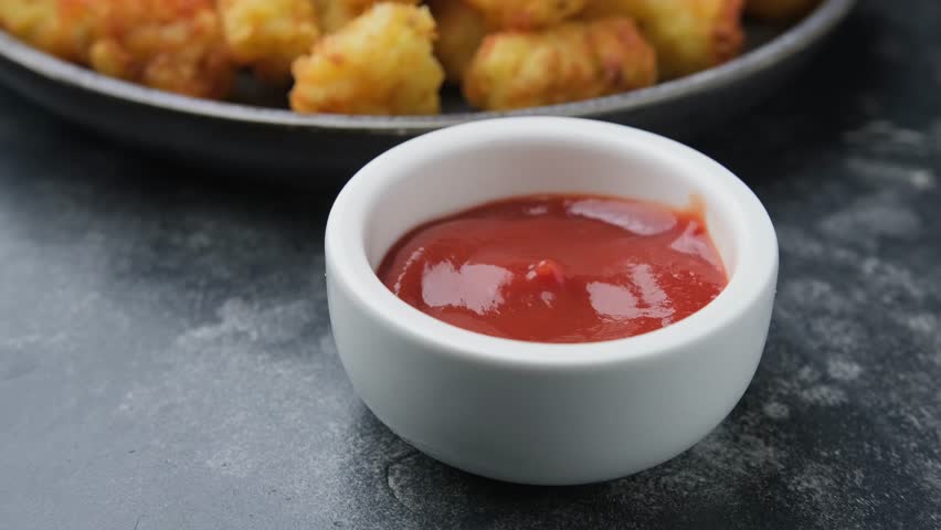 Dipping Baked Fried Tater tots Potatoes in a Ketchup