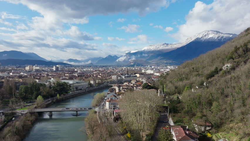 Panoramic view of Grenoble featuring the Isere river, urban landscape, and snow capped mountains in the French Alps
