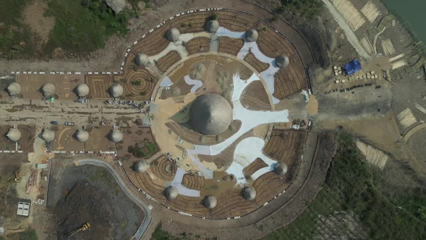 Aerial view of an innovative dome structure with radial layout under construction, showcasing modern architecture near a waterfront with surrounding land development zones.