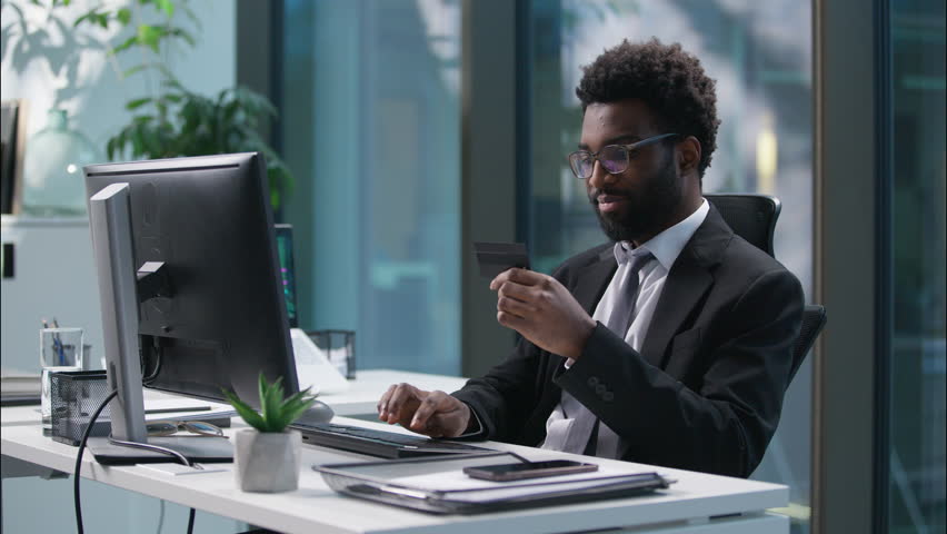 Happy African American man using credit card banking employee typing computer male paying purchase businessman smiling business guy in office online shopping client buying ecommerce app entrepreneur