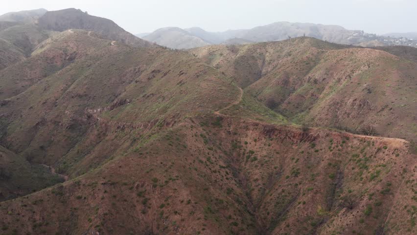 Wide rising aerial shot of the Backbone Trail above Will Rogers State Historic Park in the Palisades Fire burn scar in Southern California. 4K