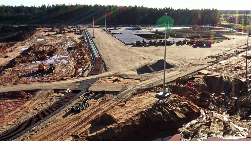 Large construction site with leveled area, materials, equipment, and lighting poles