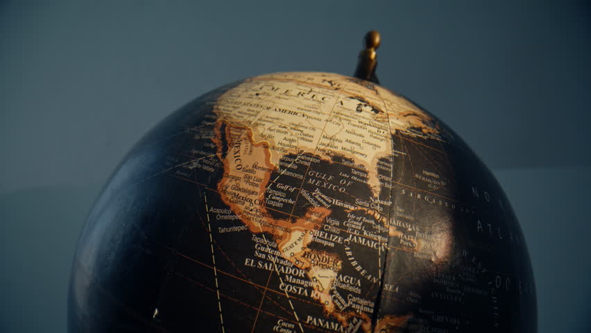 Vintage globe rotating closeup. Beautiful geographical tool spinning indoors. World countries illustrated on continents. Retro Earth model with black oceans and seas. Sphere-map for navigation concept