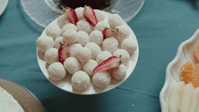 White coconut truffles arranged on a plate with fresh strawberry slices on blue table setting - Powered by Shutterstock - Get 15% off with code: PIKWIZARD15