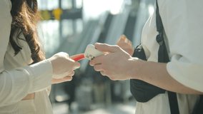 Two people are standing in a public place, one of them is holding a cell phone. The other person is holding a credit card. They seem to be in a hurry and are exchanging items - Powered by Shutterstock - Get 15% off with code: PIKWIZARD15