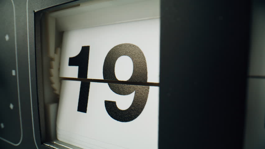 Clock calendar changing panels indoors. Electromechanical watch showing date on split-flap display closeup. Macro view digital timepiece device with time indicated by numbers. Seconds flowing concept.