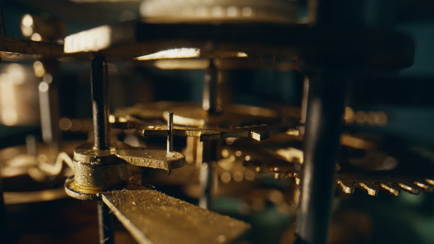 Spinning teeth of interlocked gears located inside time device closeup. Macro view inner machine turning in golden light silently. Component details working in vintage timepiece. Metal cogs moving.