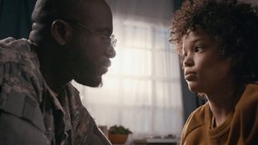 Medium close-up with lens flare of African American soldier father in camouflage uniform and young son having sincere heart to heart conversation, hugging and touching foreheads - Powered by Shutterstock - Get 15% off with code: PIKWIZARD15