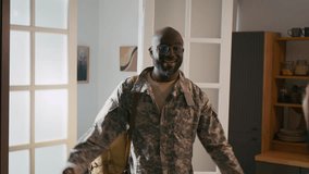 Medium shot of happy African American male soldier in khaki military uniform greeting and hugging loving wife and son in doorway, after returning home from active tour of duty - Powered by Shutterstock - Get 15% off with code: PIKWIZARD15