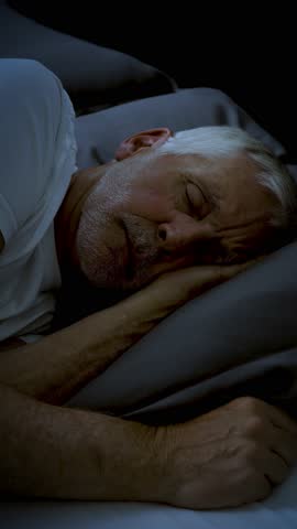 Mature adult sleeping at night. Vertical Video.
