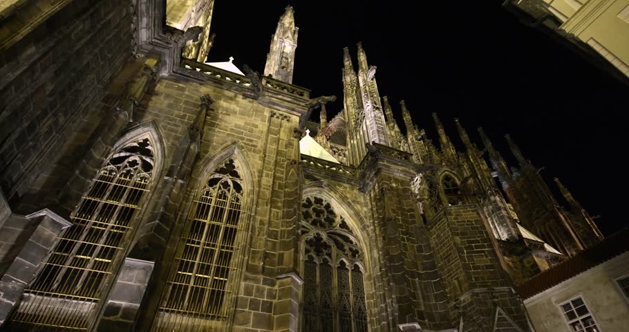 Prague St. Vitus Cathedral gothic church building detailed view at night illuminated in the dark, dramatic tall towers with gargoyles and sculptures