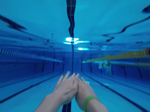 Swimmer swims butterfly swimming style in the pool. Point of View.