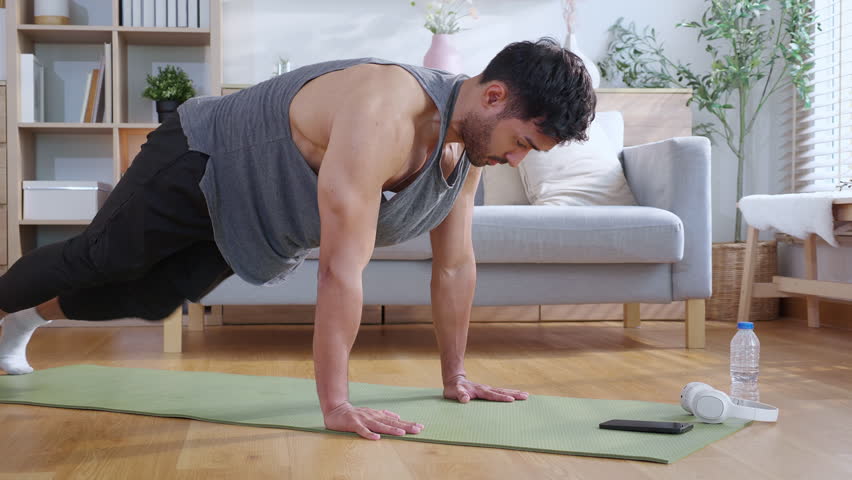 Young asian man doing pushup exercise in living room at home with determination, man training on yoga mat, bodybuilding strength and fitness for healthy lifestyle, workout routine, self-care.