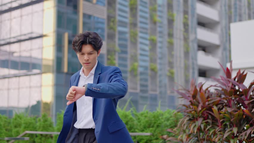 Asian young busy businessman running late to the office workplace. Attractive handsome employee man worker in formal suit holding working handbag in hurry walking outdoors in the modern urban city.