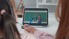 Rear view of young kid learning online class from home with mother. Adorable child student using digital tablet studying from school teacher by virtual remote online with support from mom in house. - Powered by Shutterstock - Get 15% off with code: PIKWIZARD15