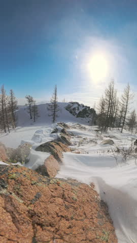 Vertical video, Wind sweeps snow particles off quiet snowy hill in remote winter landscape