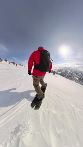 Snowboarder rides off-piste downhill through snowy forest on sunny winter day, back view. Freedom, energy, mountain spirit, healthy lifestyle, adventure and snowboarding in pure alpine nature.