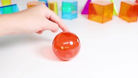 Hands interact with vibrant geometric shapes on a white table, highlighting educational play with colorful prisms and spheres - Powered by Shutterstock - Get 15% off with code: PIKWIZARD15