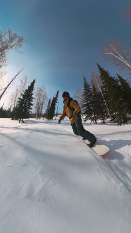 Fast paced snowboarding down pristine mountain slope framed by trees and sun. Winter adrenaline, healthy lifestyle and freedom rush through white alpine forest with active rider in motion.