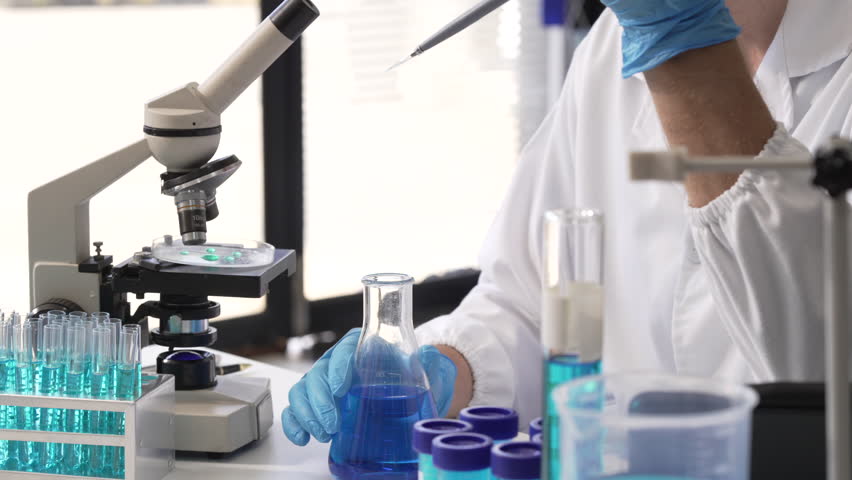 Young Caucasian male scientist works in laboratory, analyzing chemical samples with glassware and microscope. research tools, experiments, data interpretation, pharmaceutical development. - Powered by Shutterstock - Get 15% off with code: PIKWIZARD15