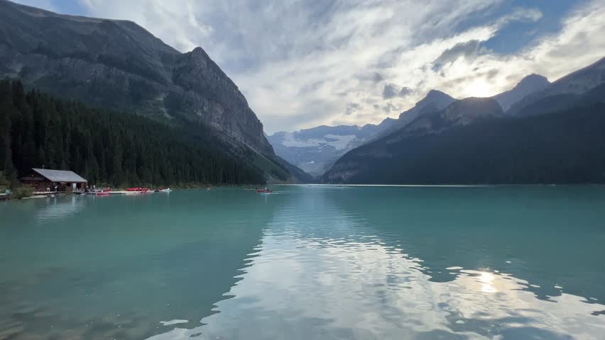 Canoes glide across the turquoise waters of Lake Louise, surrounded by towering peaks, dense evergreen forests, and dramatic skies in the heart of Banff National Park’s pristine wilderness.