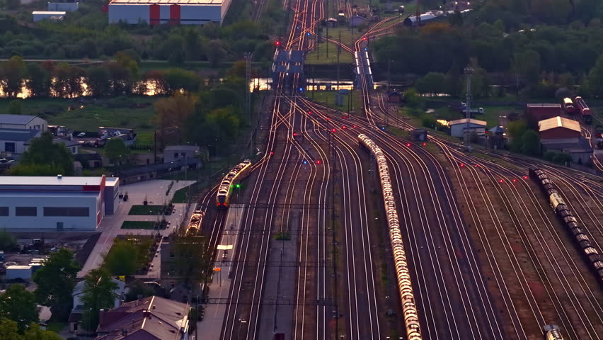 Railway junction with many converging train tracks at dusk lighting, drone view