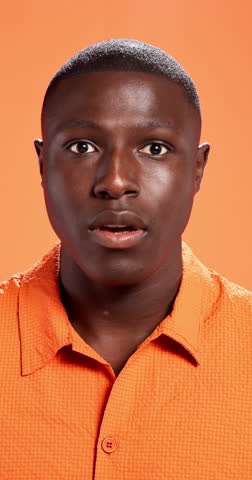 Surprise, cover mouth and face of black man in studio for reaction, facial expression and shocked. Orange background, emoji and portrait of person with hands for omg, news announcement and gossip