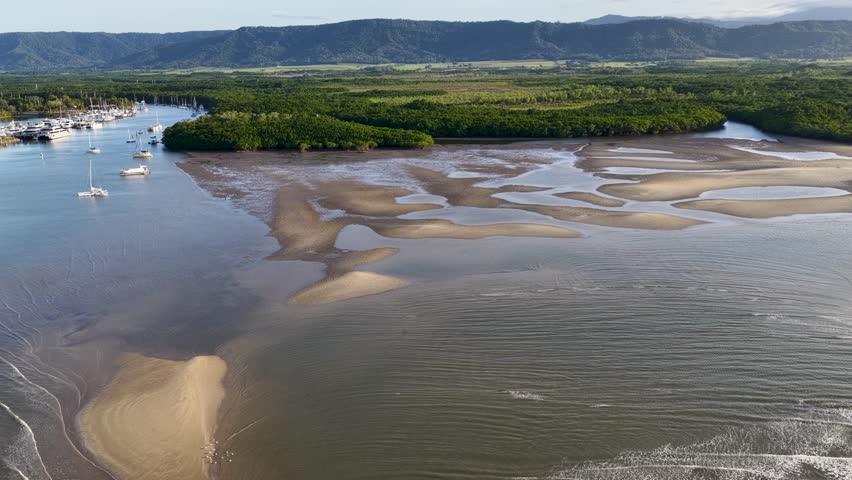 Drone footage captures the serene Daintree River, showcasing sandbanks and lush mangroves under bright daylight in Port Douglas