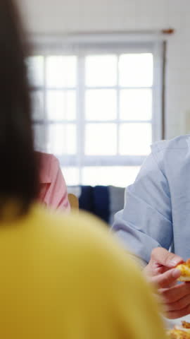Vertical Screen : Happy young friends group having lunch at home. Asia family party eat pizza food and laugh enjoy meal sitting at dining table together at house. Celebration holiday and togetherness.