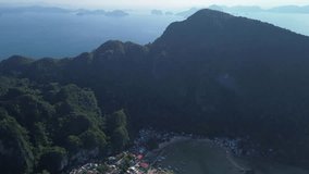 Aerial video starts above lush mountains and smoothly descends toward El Nido’s waterfront, revealing sandy beach, colorful town, and boats in emerald water. Dynamic vertical movement highlights diver - Powered by Shutterstock - Get 15% off with code: PIKWIZARD15