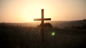 Christian cross. Wooden holy Christian cross stands in grassy field at sunset, silhouetted against warm golden sky. Peaceful rural landscape evokes faith, spirituality, hope and remembrance religion  - Powered by Shutterstock - Get 15% off with code: PIKWIZARD15