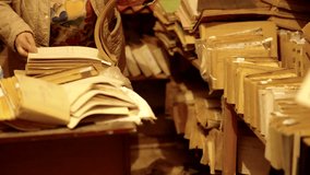 Woman browsing through old paper files in a cluttered archive room. Vintage documents, yellowed folders, and stacked paperwork create a nostalgic atmosphere of historical record keeping - Powered by Shutterstock - Get 15% off with code: PIKWIZARD15