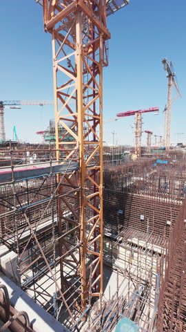 Vertical handheld footage of concrete distribution boom at construction site. Construction machinery. Concrete placing boom
