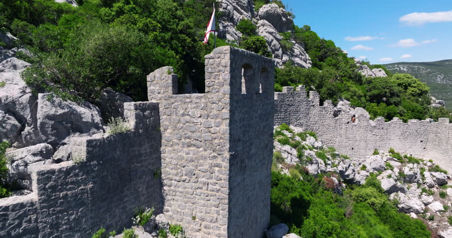 Flag On Tower Of Defensive Walls In Ston, Croatia. - aerial pullback shot