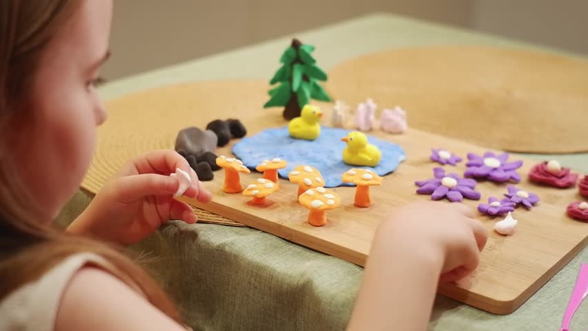 Child meticulously arranges colorful play dough figures on a wooden board, crafting a miniature garden scene