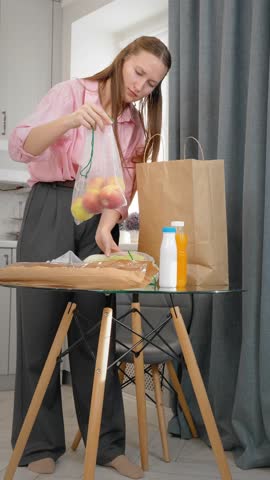 Woman unpacking groceries at home after shopping in supermarket buying food. Satisfied young online marketplace shopper unpacking a box of products ordered online with courier delivery vertical video