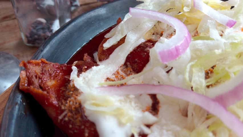 Delicious enchiladas enmoladas with lettuce, onions, and sour cream in a close-up shot