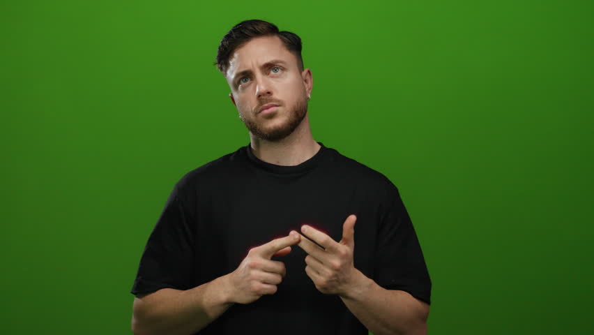 Young man with beard counting on fingers against isolated green wall, showcasing focus and thought.