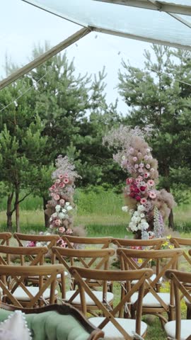 Wooden chairs arranged under a tent for a wedding ceremony. vertical video