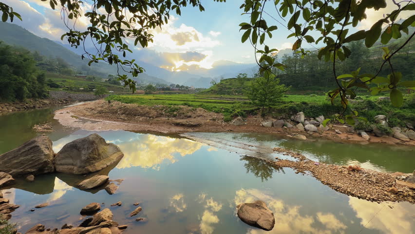 Tranquil river landscape in Sa Pa, Vietnam, with mountain reflections, golden skies, and peaceful rural nature. Serene, untouched beauty at sunset.