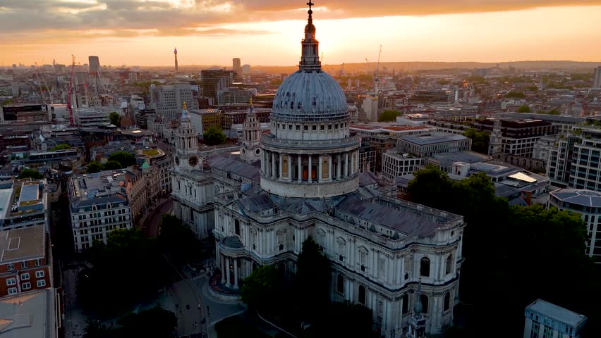 Aerial view of the St. Pauls Cathedral in London, England, during sunset with golden sunlight behind the skyline