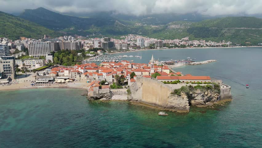 Aerial drone view of Budva Old Town Stari Grad in Montenegro. Budva Riviera with mountains and blue seas. European travel holiday 