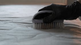 Close-up footage of a woman gloved hands cleaning a visibly stained mattress using soap and a scrubbing brush. Perfect for topics like hygiene, DIY cleaning, stain removal, and household care. - Powered by Shutterstock - Get 15% off with code: PIKWIZARD15