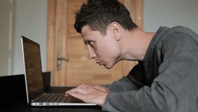 Young man with poor posture leaning close to laptop screen while typing, indicating eye strain and digital fatigue. Guy slouching over laptop at home. Hunched back - Powered by Shutterstock - Get 15% off with code: PIKWIZARD15