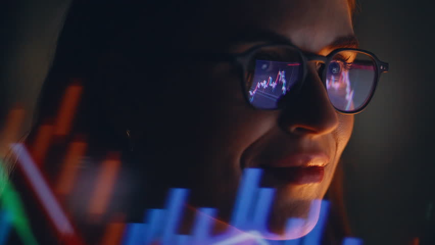 Late evening female trader studying graphs wearing glasses watching laptop display closeup. Happy digital currency expert managing bitcoin charts focused on financial analysis solo in office space