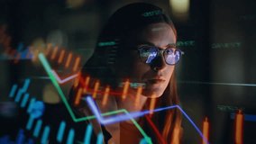 Stock market trader working investment charts in hologram at night closeup. Graphs diagrams projected on face and reflecting in glasses. Financial analyst digital businesswoman selling and buying  - Powered by Shutterstock - Get 15% off with code: PIKWIZARD15