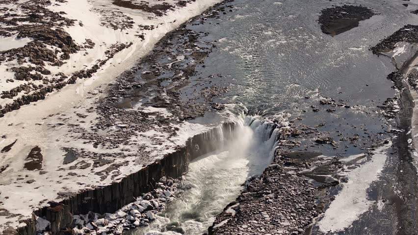 aerial of Selfoss waterfall in snowy landscape with frozen river and basalt cliffs in Iceland